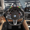 Front view of a BMW G/F chassis, M steering wheel in carbon fiber, black perforated leather, driving assistant pro buttons, m color accents and led shift lights